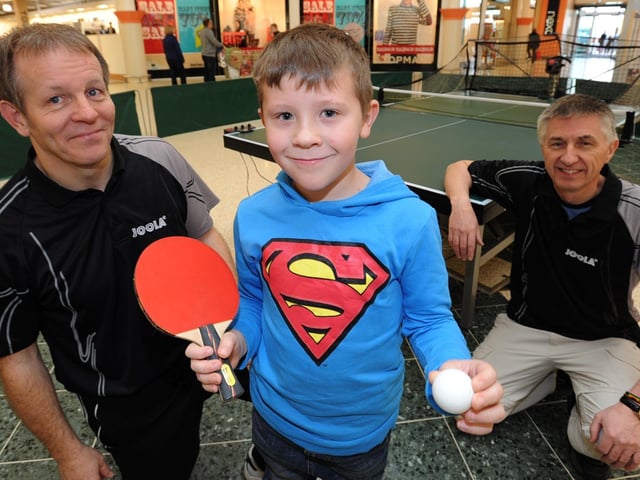 Rhys Young, 8, from Whittlesey, tries table tennis at Serpentine Green during a recruitment drive by Hampton Table Tennis Club members (left) John Morris and (right) chairman Robin Wilkin.