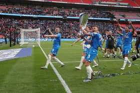 Harrison Burrows lifts the trophy in front of the adoring Posh fans. Photo: Joe Dent.