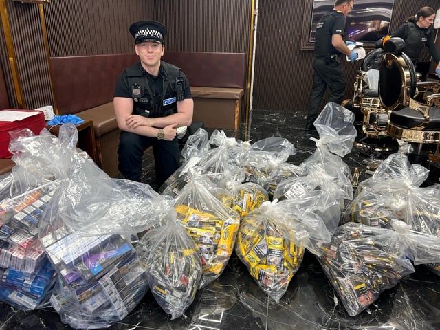 An officer with some of the cigarettes and tobacco seized