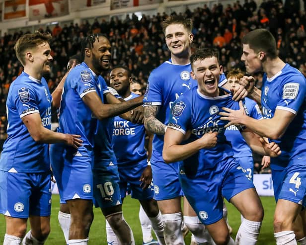 Harrison Burrows (second right) and Ricky-Jade Jones (second left) in the middle of Posh celebrations at Blackpool. Photo Joe Dent/theposh.com.