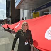 Fatima Alissa and  Mark Murray from HELP with volunteers holding the 25 metre red flag for the Coronation.