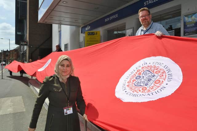 Fatima Alissa and  Mark Murray from HELP with volunteers holding the 25 metre red flag for the Coronation.