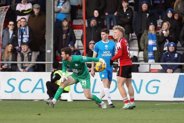 Jed Steer of Peterborough United releases the ball against Lincoln City watched by former Posh player Joe Taylor. Photo: Joe Dent/theposh.com.