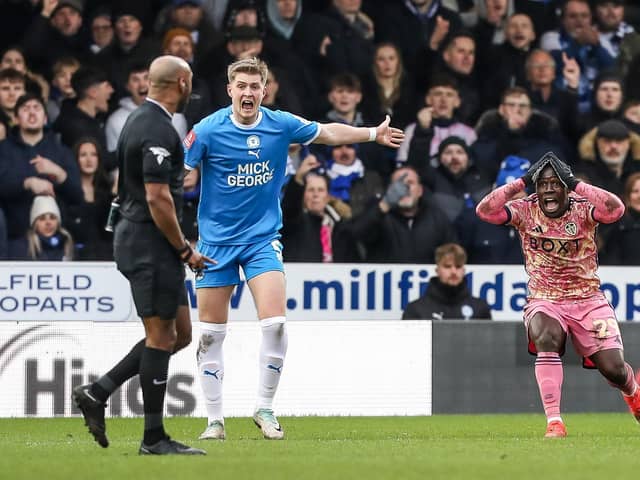 Josh Knight of Posh and Wilfried Gnonto of Leeds United can't believe what referee Sam Allison has ignored. Photo: Joe Dent/theposh.com.