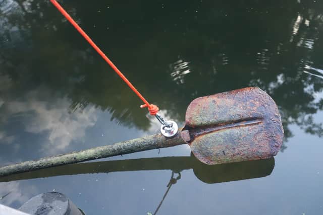 Thankfully no danger here: a magnet fisherman retrieving a rusty shovel out of the water.