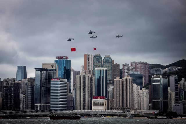Helicopters fly past with the Hong Kong and Chinese flags during a flag-raising ceremony to celebrate the 25th anniversary of the city's handover from Britain to China, in Hong Kong on July 1, 2022. (Photo by ISAAC LAWRENCE/AFP via Getty Images)