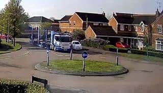 A car transporter towers over a residents' vehicle at the approach to a mini roundabout on the way to the East of England Showground.