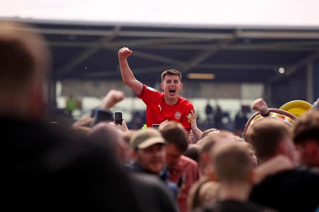 Kell Watts is carried of the pitch by Wigan fans after promotion from League One waa secured last season. (Photo by Charlotte Tattersall/Getty Images).