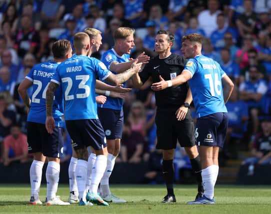 Posh players protest against referee Dean Whitestone's decision not to award them a penalty against Morecambe. Photo: Paul Marriott.