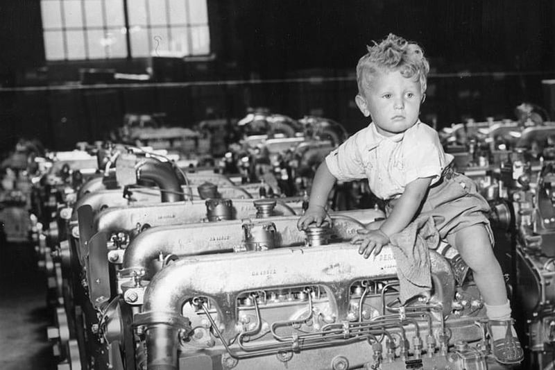 Two year-old Martin Nichols climbs on a diesel engine at the Perkins engine factory in Peterborough, during a family open day at the works, 8th July 1955.