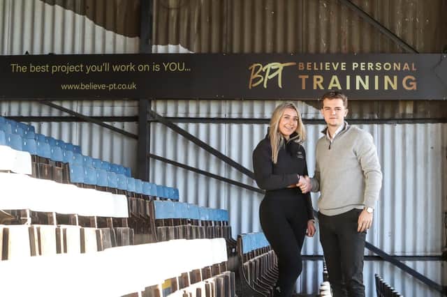 Believe PT owner Ellie Smith and Posh Commercial Executive Bobby Copping in front of the new sign at Peterborough United's London Road Stadium.
