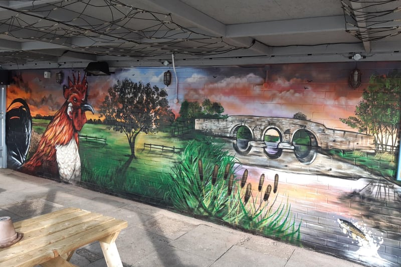 The Cock Inn at Werrington's smoking shelter with mural by Steve Crowe