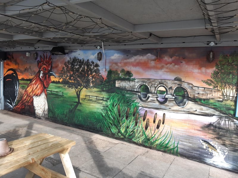 The Cock Inn at Werrington's smoking shelter with mural by Steve Crowe