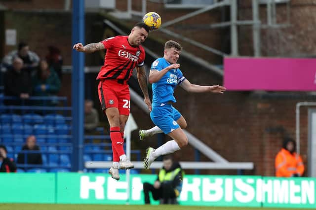 Harrison Burrows of Peterborough United challenges for the ball with Josh Magennis of Wigan Athletic. Photo: Joe Dent/theposh.com.