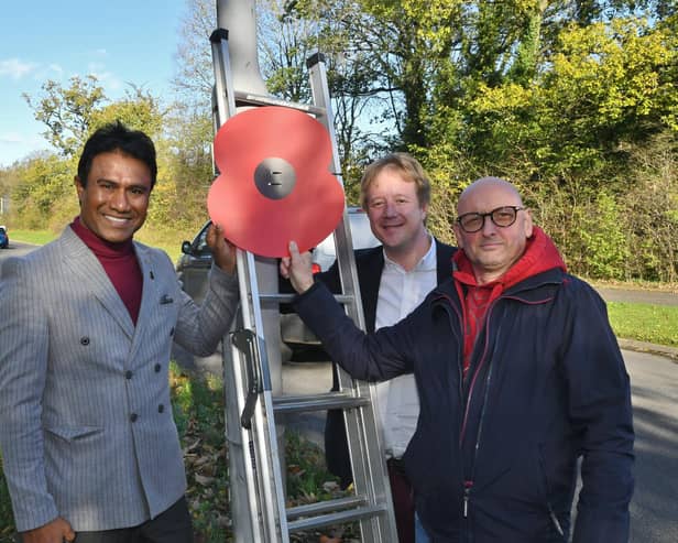 MP for Peterborough Paul Bristow, Zillur Hussain and Cllr Charles Fenner putting up giant poppies on lamp posts in Bretton.