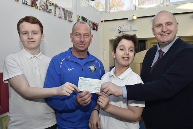 Andy Simmonds from the Ploughman Pub, Werrington presents a cheque to  Barry Leslie, assistant head teacher of Heltwate School along with two of his pupils in 2020.