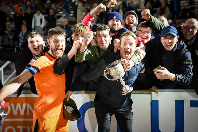 Jimmy Dean celebrates a Peterborough Sports trophy with the club's fans and club captain Richard Jones (orange). Photo: James Richardson.