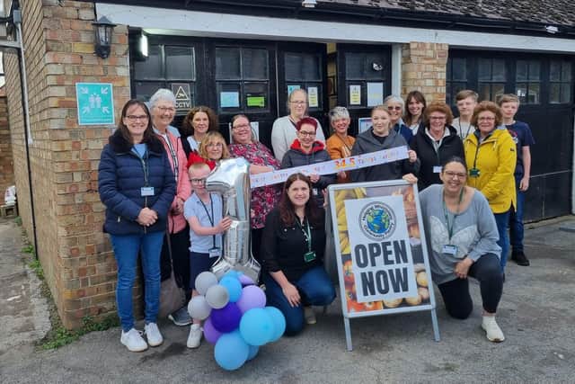 Some of The Community Pantry's volunteers celebrating the initiative's first anniversary with the Chairs of Helping Whittlesey Anna Foster (left) and Layla Waters (right) kneeling by the board.
