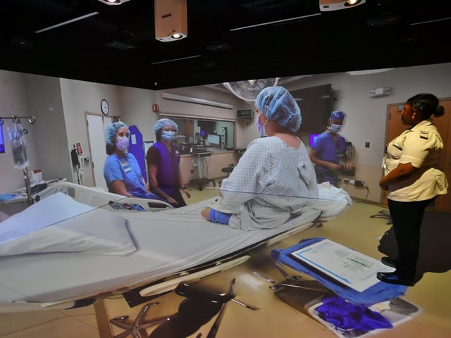 A trainee nurse watches a scene from a simulated hospital ward at XRP eXtended Reality at ARU Peterborough