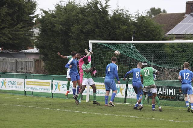 Mario Neves (partly hidden) scores for FC Peterborough (green) against Cornard. Photo Tim Symonds.