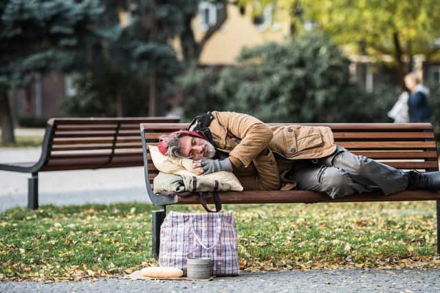 Rough sleeper on a bench in a park.