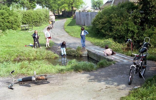 A scene that will bring back memories for those of a certain age, with kids 'tiddling' for minnows while casting aside their bikes which would be worth a fortune today! The location is the Lode crossing at Stanground at the back of the church and the image dates to the very early 1980s (image: Peterborough Images Archive)