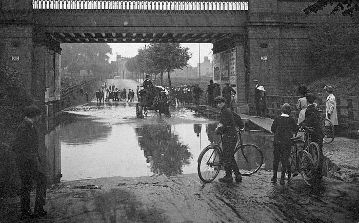 All too familiar - the railway bridge on Oundle Road! The flood water accumulated to such a depth during the downpours of 1912 that pedestrians had to (carefully) make good use of an elevated timber walkway, seen to the right (Peterborough Images Archive)