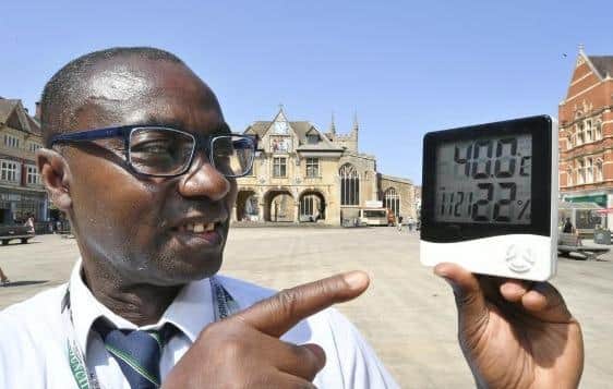 Ernest Mensah-Sekyere with a digital thermometer reading 40 degrees in direct sunlight at Cathedral Square, Peterborough