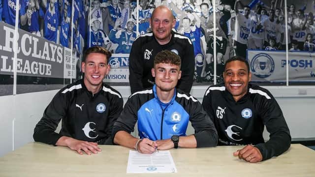 Reuben Marshall (centre. front) signs his first professional contract flanked by Posh Academy staff. Photo: Joe Dent/theposh.com.
