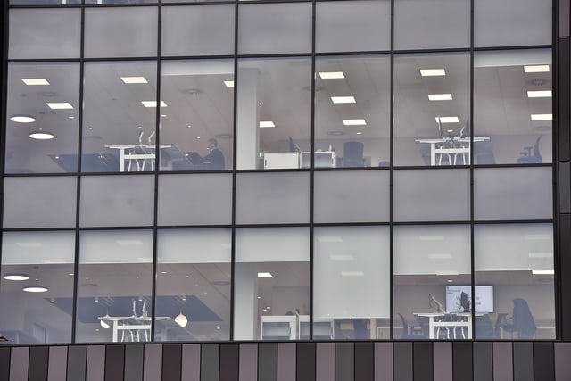 The glazed side of the Government Offices at Fletton Quays, Peterborough, which shows desks and screen and some people at work.