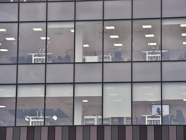 The glazed side of the Government Offices at Fletton Quays, Peterborough, which shows desks and screen and some people at work.
