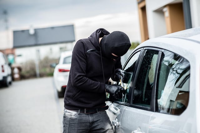 Car thief trying to break into a car with a screwdriver.