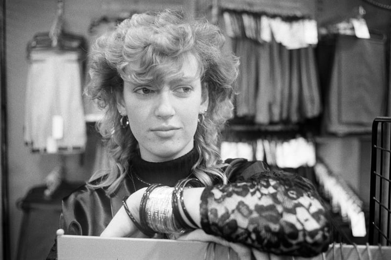Youth Training Scheme (YTS) worker Amanda Fields watches over the clothes racks in Collier menswear shop in Peterborough, 1985.

