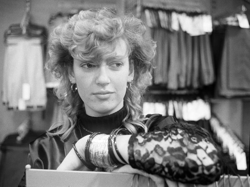 Youth Training Scheme (YTS) worker Amanda Fields watches over the clothes racks in Collier menswear shop in Peterborough, 1985.

