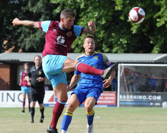Ross Watson of Deeping Rangers makes a clearance at Spalding watched by Toby Hilliard. Photo: Chris Lowndes.