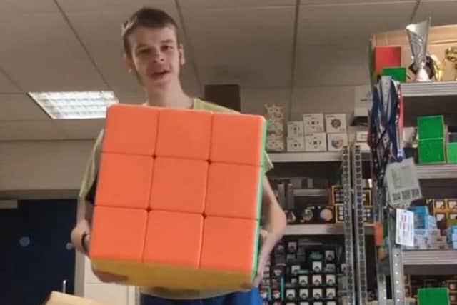 Daniel holding a giant cube in his warehouse