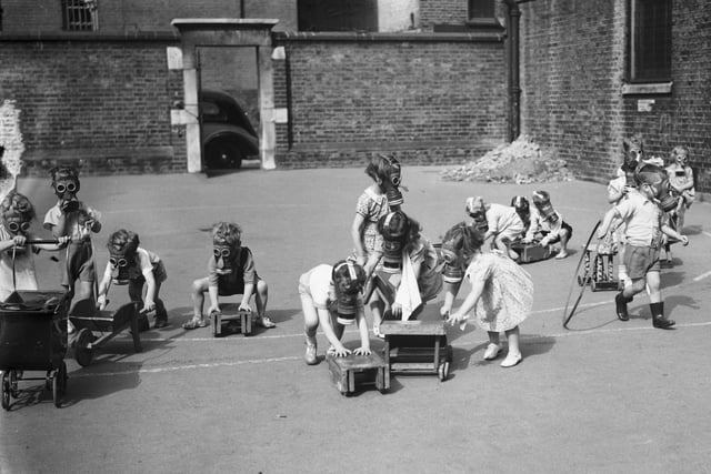 Children wearing their gas masks while playing in the playground (Photo by Keystone/Hulton Archive/Getty Images)