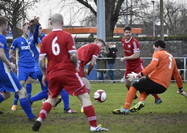 Mark Jones (centre, red) of Peterborough Sports failed to convert this early chance at Spalding. Photo: James Richardson.