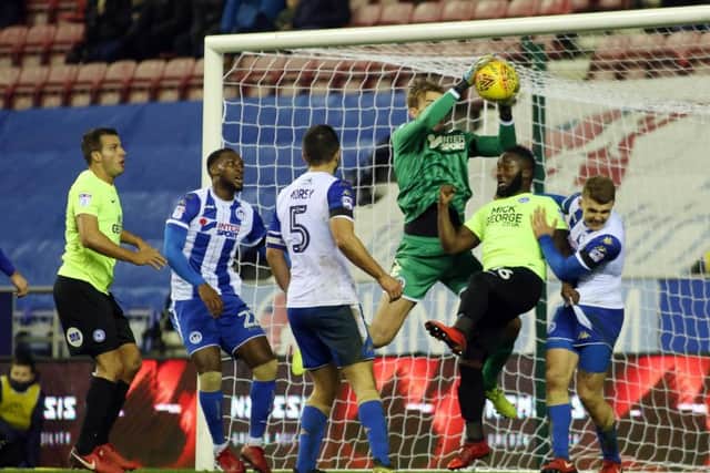 Wigan goalkeeper Christian Walton catches a corner under pressure from Posh substitute Junior Morias. Photo: Joe Dent/theposh.com.