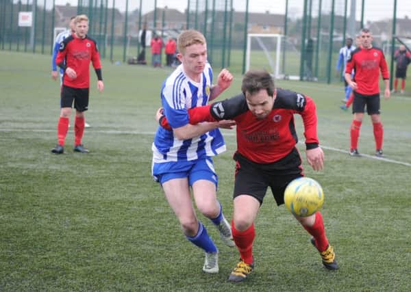 Netherton's Ben Daly (red) holds off a Peterborough Sports player during a tough President's Shield tie at the Grange. Photo: David Lowndes.