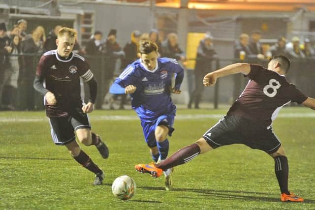 Matt Sparrow (blue) scored for Yaxley against Newport Pagnell.