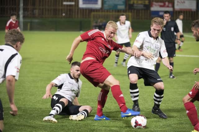 Michael Frew (red, centre) scored the only goal of the game for Wisbech against Yaxley.