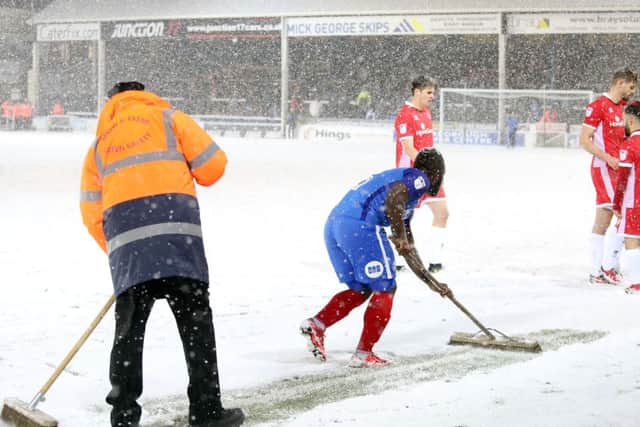 Posh substitute Junior Morias helps to clear the pitch markings during a break in play against Walsall. Photo: Joe Dent/theposh.com.