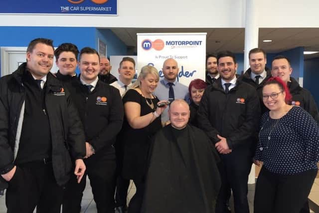 Daniel Woodward has his hair shaved by Jess Whiting as his Motorpoint colleagues watch.