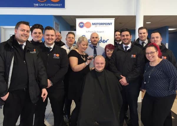 Daniel Woodward has his hair shaved by Jess Whiting as his Motorpoint colleagues watch.