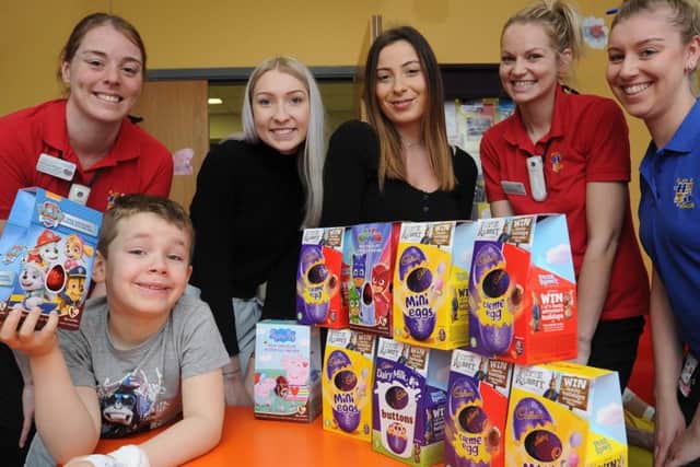 Charlotte Batty and Chantelle Freshwater from Unique Employment Service with City Hospital Amazon Ward staff Nicola Wright, Chelsea Perry and Hannah Smith with one of the ward's young patients Harry Cartwright receiving easter eggs from Unique EMN-180327-155917009