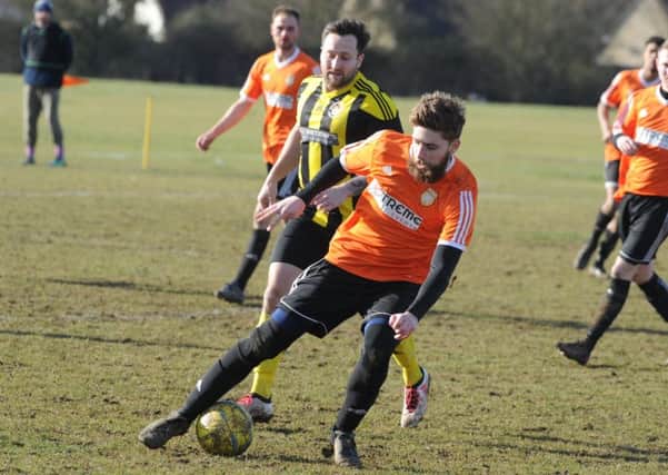 Thorney FC (orange) in action.