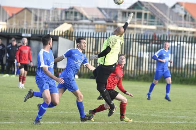 Netherton's Tom Randall (red) waits to pounce as Whittlesey goalkeeper Anthony Jackson tries to deal with a high ball. Photo: David Lowndes.