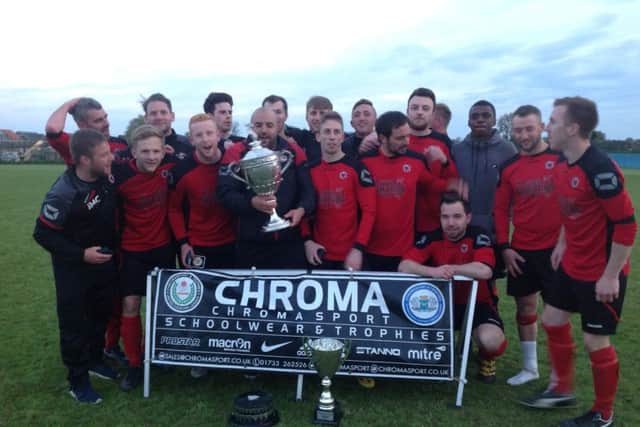 Netherton manager Jon Harrison has his hands on the Peterborough Premier Division trophy watched by his title-winning team.