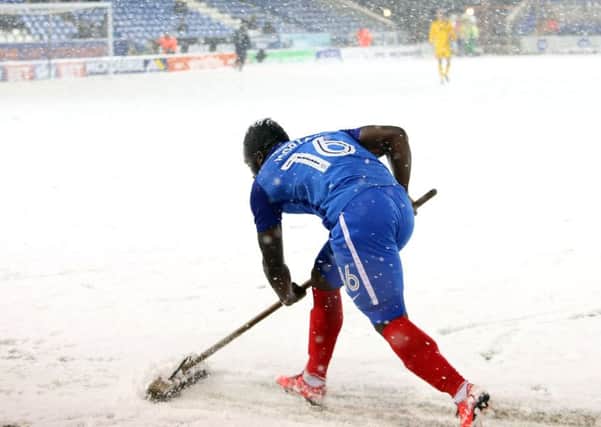 Junior Morias clearing snow off the Posh pitch.